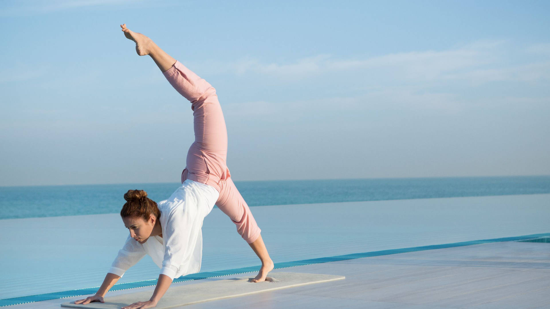 A woman doing yoga by the sea